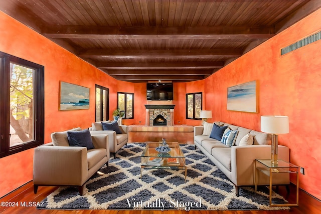 living room with wooden ceiling, hardwood / wood-style floors, beam ceiling, and a stone fireplace