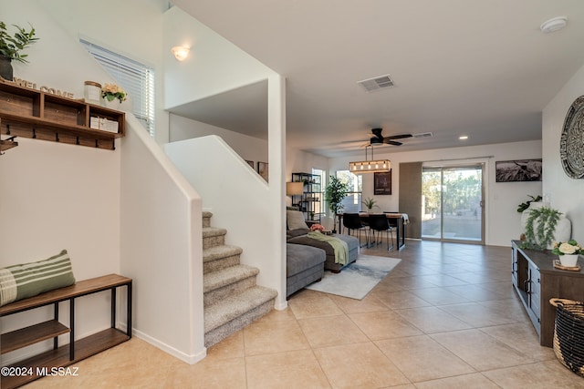 tiled dining space featuring ceiling fan with notable chandelier and plenty of natural light