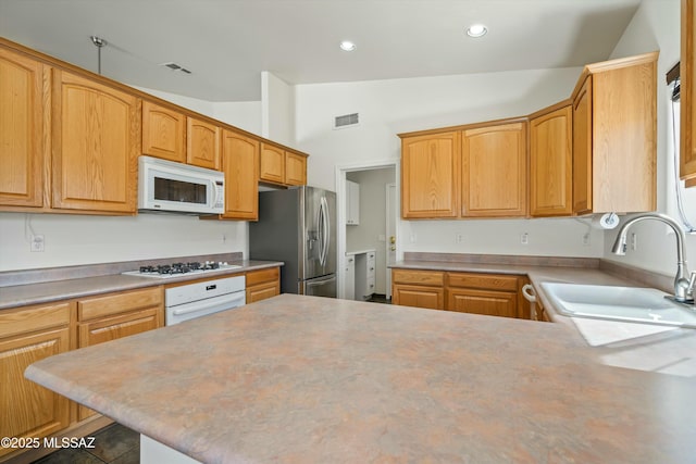 kitchen with vaulted ceiling, light countertops, white appliances, and a sink