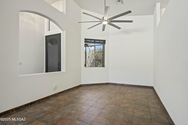 spare room with ceiling fan, a high ceiling, visible vents, and baseboards