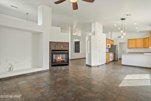 unfurnished living room with a ceiling fan, baseboards, visible vents, and a tiled fireplace