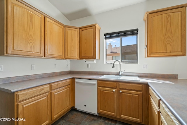 kitchen featuring light countertops, stone finish floor, white dishwasher, and a sink