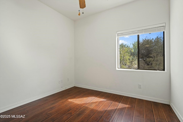 unfurnished room featuring baseboards, dark wood finished floors, and a ceiling fan