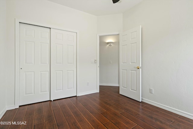 unfurnished bedroom with a closet, dark wood finished floors, and baseboards