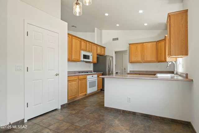 kitchen with lofted ceiling, light countertops, appliances with stainless steel finishes, a sink, and a peninsula