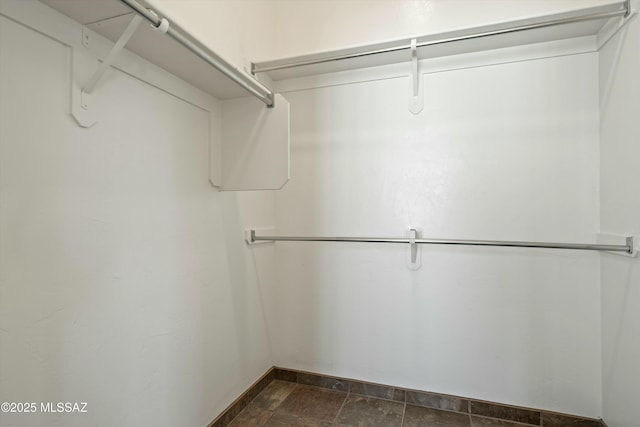 spacious closet featuring stone finish floor