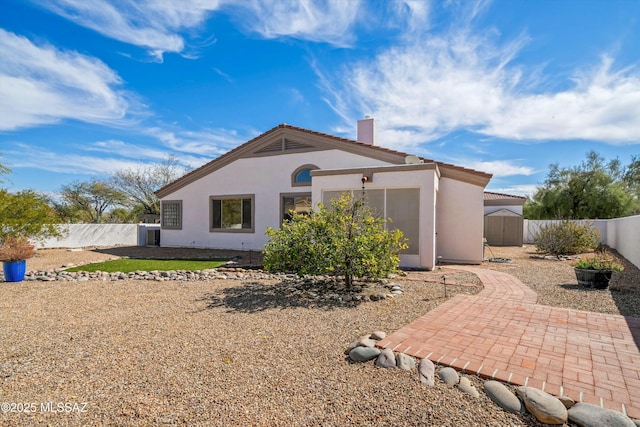 rear view of house with a fenced backyard, a patio, a chimney, and stucco siding