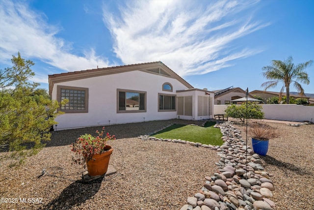 rear view of property featuring fence and stucco siding