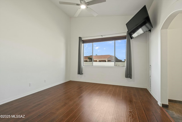 spare room featuring a ceiling fan, dark wood-style flooring, and baseboards