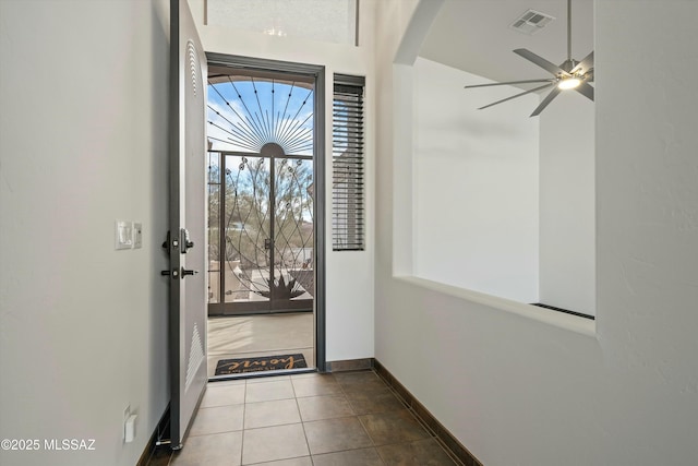 entryway featuring arched walkways, light tile patterned floors, visible vents, ceiling fan, and baseboards