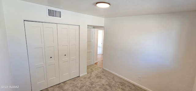 unfurnished bedroom with a closet and light colored carpet