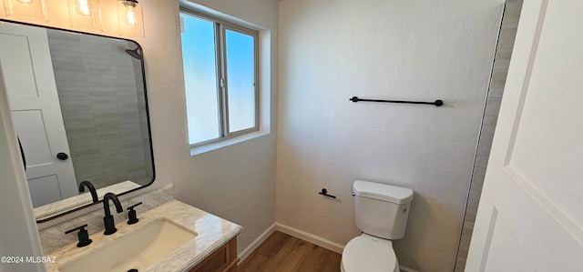 bathroom with toilet, vanity, and wood-type flooring