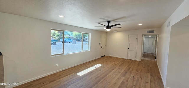 spare room with vaulted ceiling, a textured ceiling, light wood-type flooring, and ceiling fan