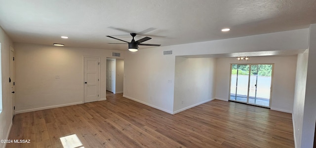 spare room with wood-type flooring, a textured ceiling, and ceiling fan with notable chandelier