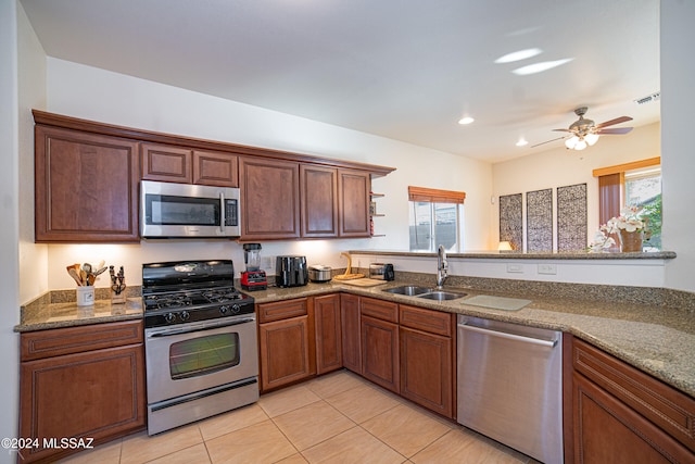 kitchen with sink, light tile patterned floors, stone counters, and appliances with stainless steel finishes