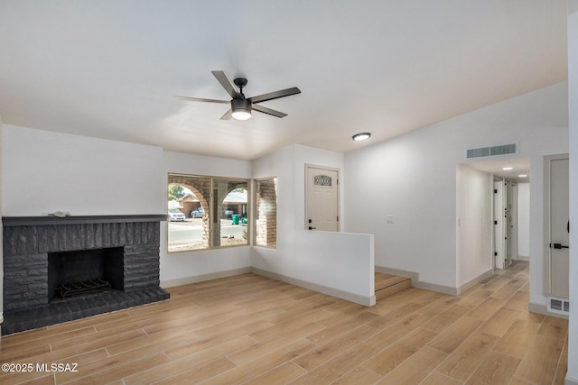 unfurnished living room with a brick fireplace, light wood-type flooring, lofted ceiling, and ceiling fan