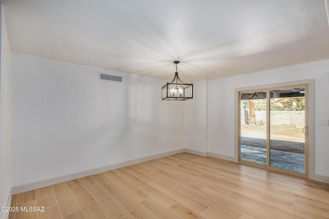 empty room featuring a chandelier and light hardwood / wood-style flooring