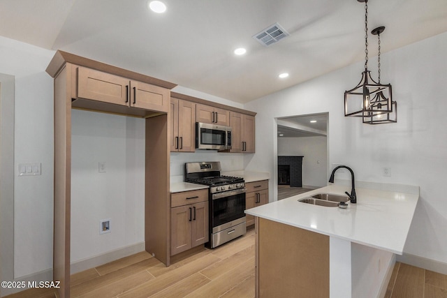 kitchen featuring vaulted ceiling, appliances with stainless steel finishes, decorative light fixtures, sink, and kitchen peninsula