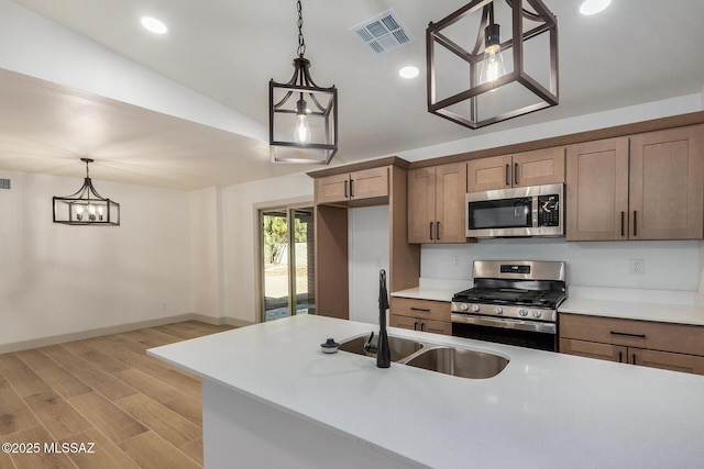 kitchen featuring hanging light fixtures, light hardwood / wood-style floors, sink, and appliances with stainless steel finishes