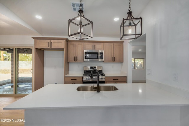 kitchen featuring appliances with stainless steel finishes, plenty of natural light, and decorative light fixtures