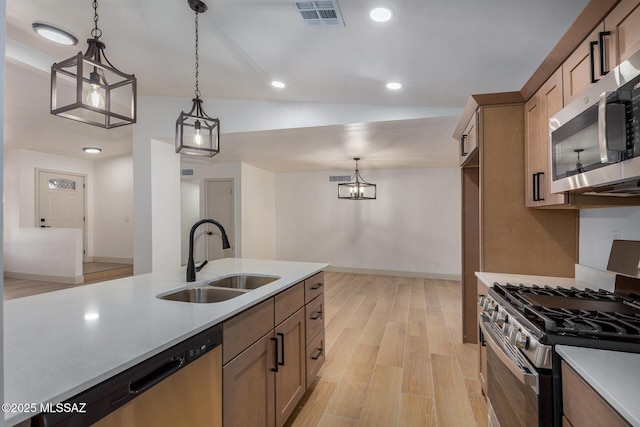 kitchen with sink, vaulted ceiling, light hardwood / wood-style flooring, pendant lighting, and stainless steel appliances