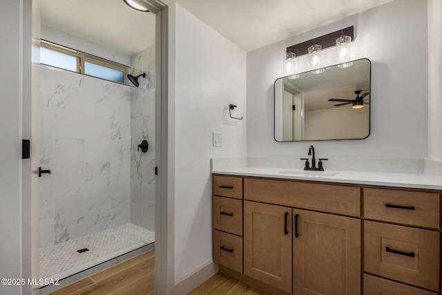 bathroom featuring a tile shower, vanity, hardwood / wood-style flooring, and ceiling fan