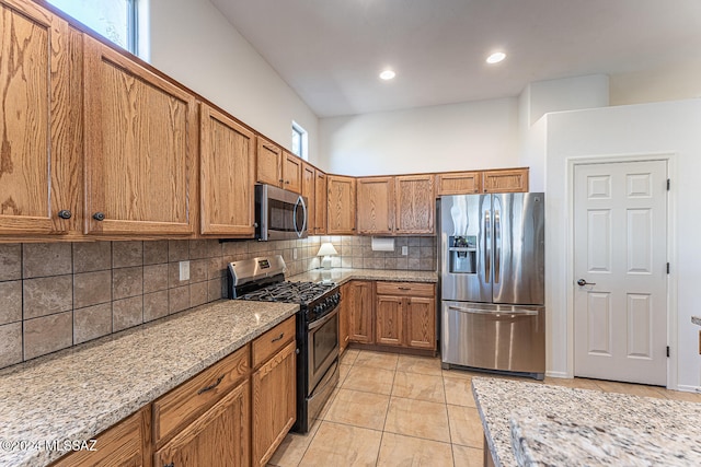 kitchen featuring light stone counters, stainless steel appliances, decorative backsplash, and light tile patterned flooring