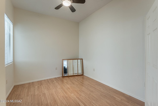 empty room with lofted ceiling, light wood-type flooring, and ceiling fan