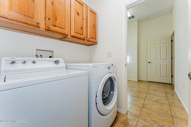 clothes washing area featuring cabinets and washing machine and dryer