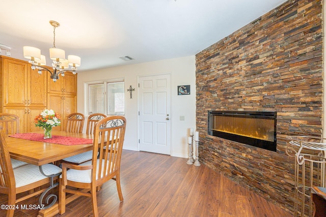 dining area featuring a fireplace, dark wood-type flooring, and a notable chandelier