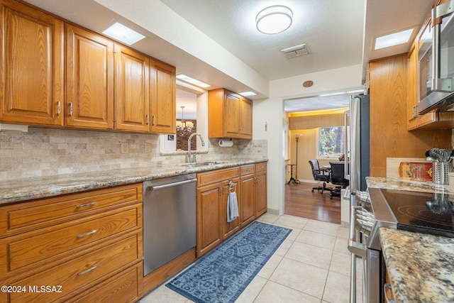 kitchen with light tile patterned flooring, light stone countertops, sink, and appliances with stainless steel finishes