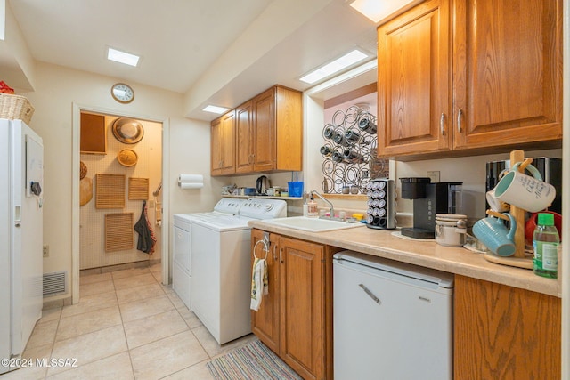 clothes washing area with cabinets, separate washer and dryer, sink, and light tile patterned floors