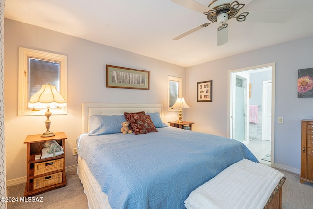 bedroom featuring ceiling fan, light colored carpet, and ensuite bath