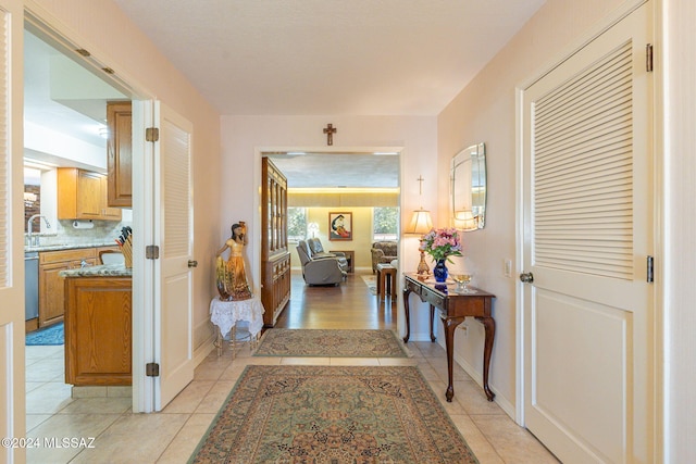 corridor featuring light tile patterned floors and sink