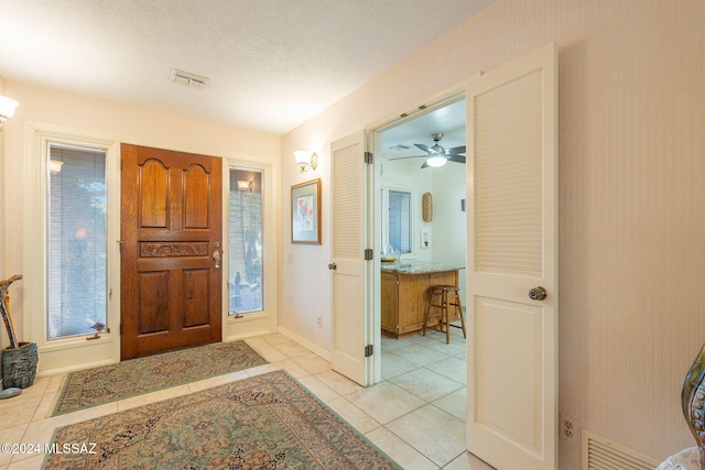 tiled entryway featuring ceiling fan and a textured ceiling