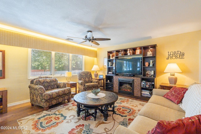 living room with ceiling fan, a textured ceiling, and hardwood / wood-style flooring