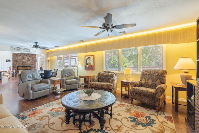 living room with a fireplace, ceiling fan, hardwood / wood-style floors, and a textured ceiling