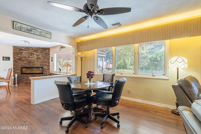 dining room featuring ceiling fan, a fireplace, and dark hardwood / wood-style floors