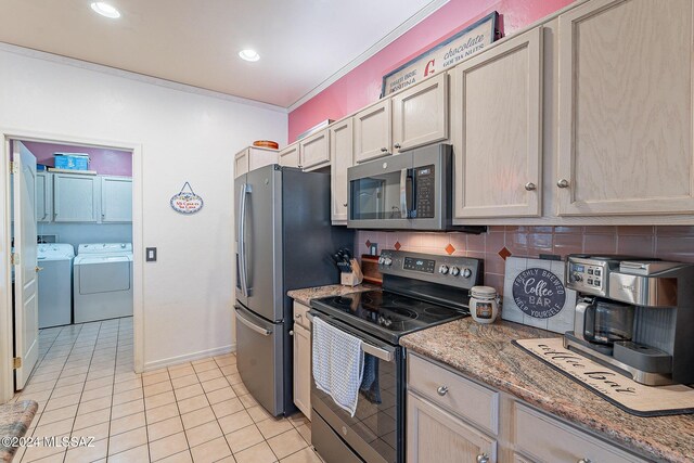 kitchen with appliances with stainless steel finishes, washer and dryer, light tile patterned floors, tasteful backsplash, and light stone counters