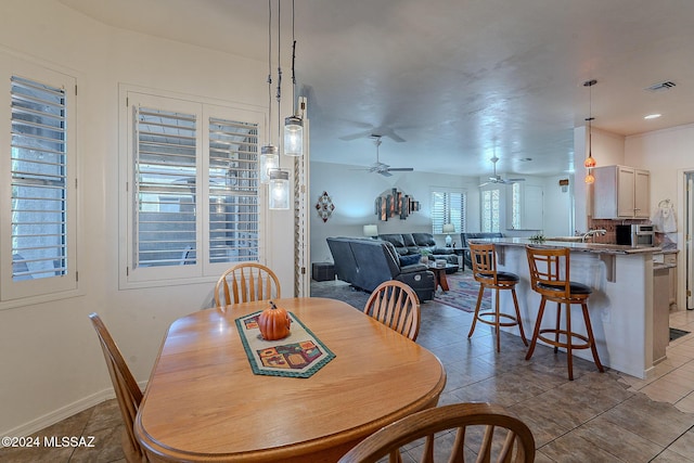 dining area with a ceiling fan, tile patterned floors, and baseboards