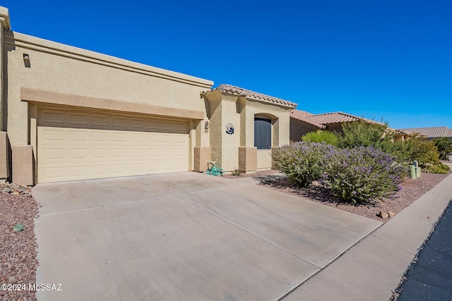 mediterranean / spanish-style home with stucco siding, driveway, an attached garage, and a tiled roof