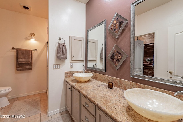 bathroom with toilet, tile patterned floors, baseboards, and double vanity