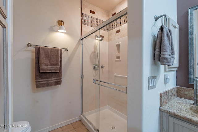 full bathroom with a shower stall, toilet, vanity, tile patterned floors, and baseboards