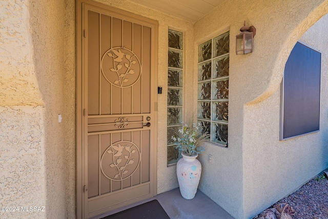 doorway to property with stucco siding and covered porch