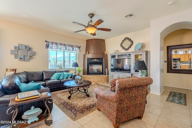 tiled living room featuring ceiling fan and a tile fireplace