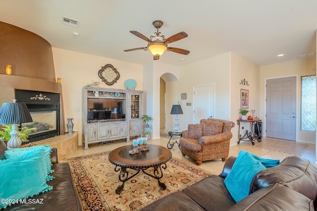 tiled living room featuring a tiled fireplace and ceiling fan