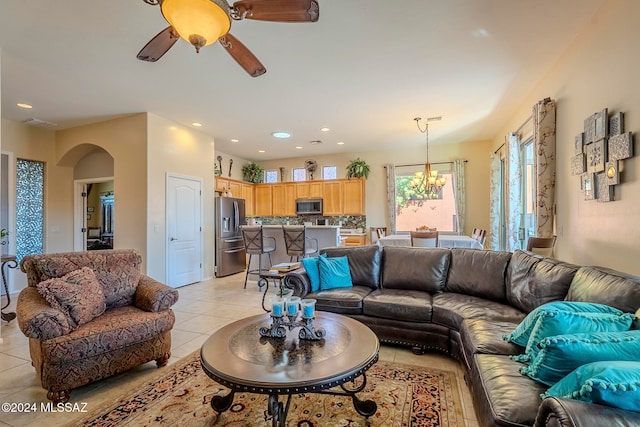 living room with ceiling fan with notable chandelier and light tile patterned floors