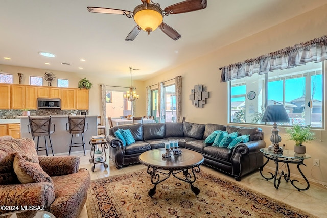 living room with light tile patterned flooring and ceiling fan with notable chandelier