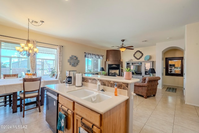 kitchen featuring light tile patterned flooring, a center island with sink, decorative light fixtures, sink, and ceiling fan with notable chandelier