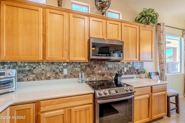 kitchen with light tile patterned floors, backsplash, and appliances with stainless steel finishes